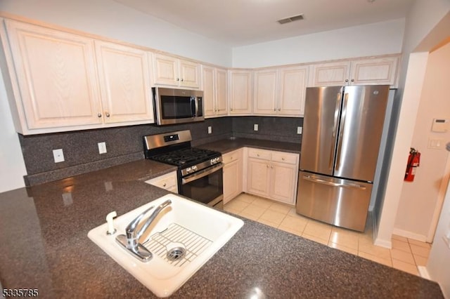 kitchen featuring tasteful backsplash, stainless steel appliances, sink, and light tile patterned floors