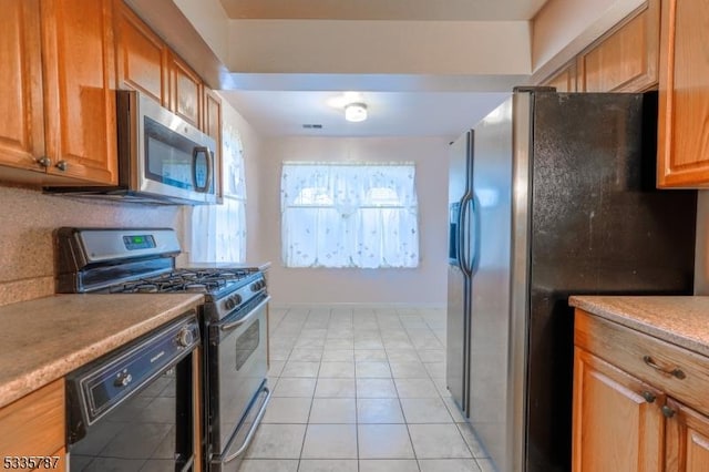 kitchen with brown cabinets, appliances with stainless steel finishes, light countertops, baseboards, and light tile patterned floors