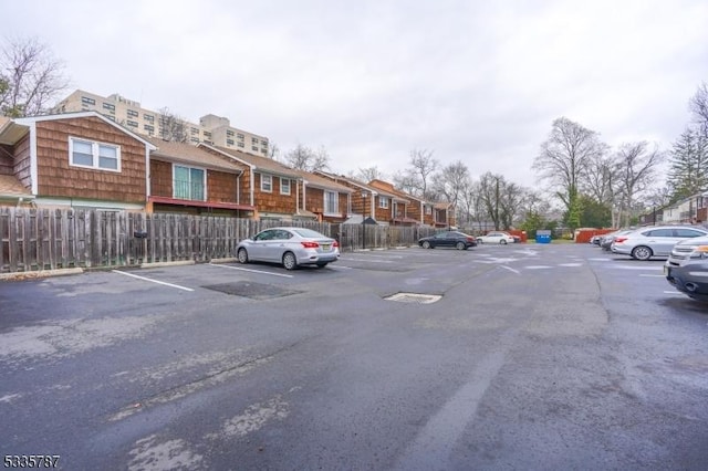 uncovered parking lot with fence and a residential view