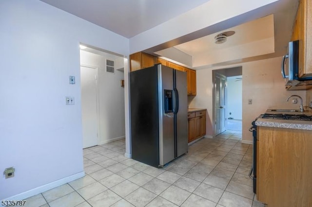 kitchen with visible vents, brown cabinets, a sink, stainless steel microwave, and refrigerator with ice dispenser