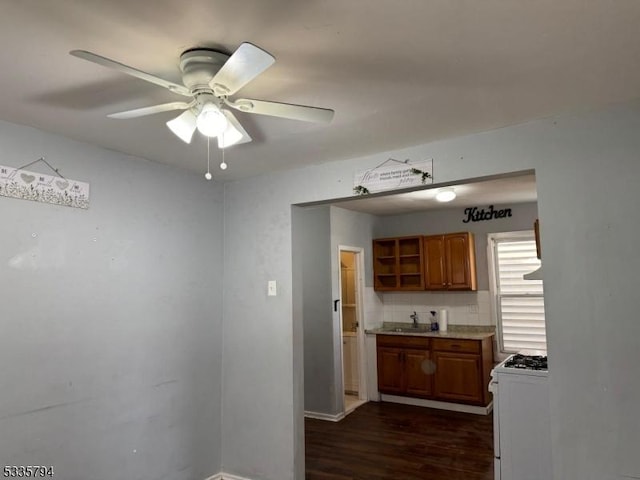 kitchen with tasteful backsplash, white gas range, sink, dark hardwood / wood-style flooring, and ceiling fan