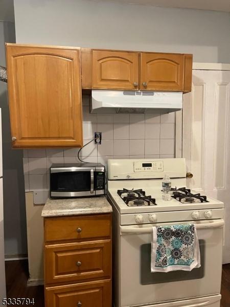 kitchen with tasteful backsplash, white gas range, and dark hardwood / wood-style flooring