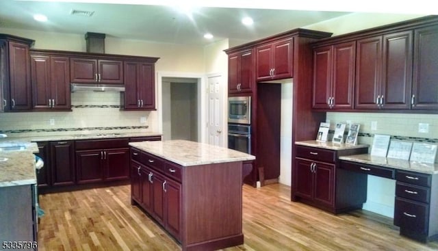 kitchen with tasteful backsplash, wood-type flooring, appliances with stainless steel finishes, and a center island