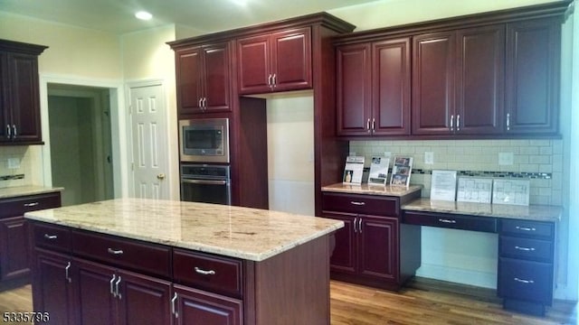 kitchen with stainless steel microwave, dark hardwood / wood-style floors, a kitchen island, oven, and decorative backsplash