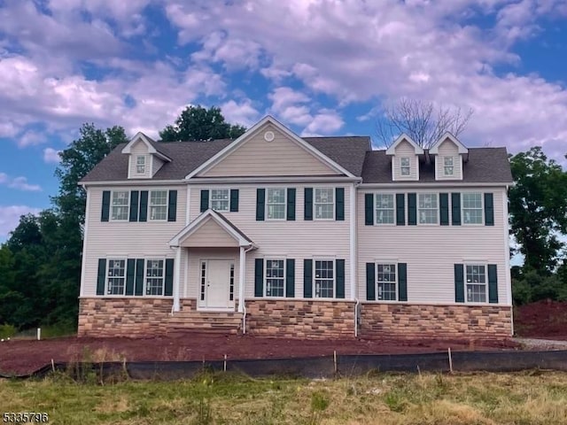 colonial inspired home with stone siding and a shingled roof