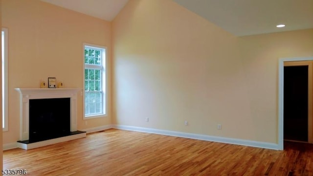 unfurnished living room featuring lofted ceiling and light hardwood / wood-style floors