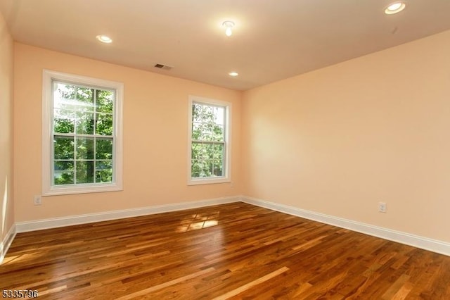 unfurnished room with a healthy amount of sunlight and hardwood / wood-style floors