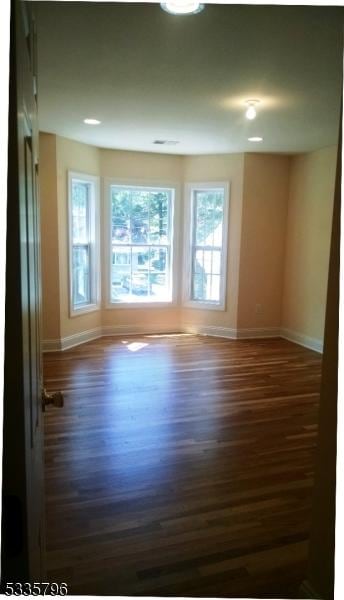 spare room with baseboards and dark wood finished floors