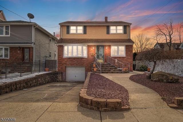 view of front of house featuring a garage, fence, concrete driveway, and brick siding