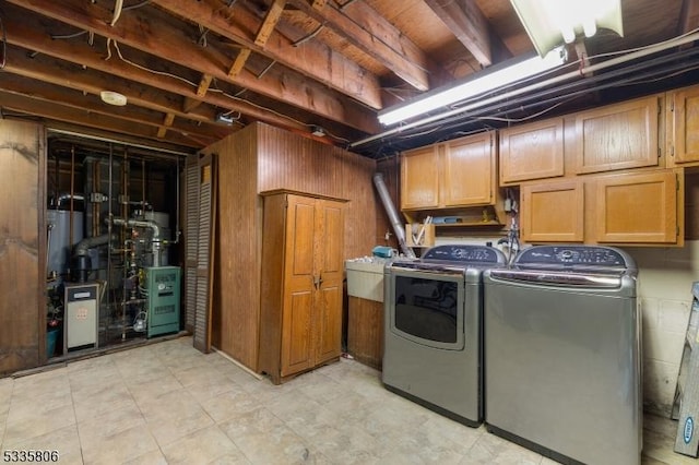 clothes washing area with a heating unit, independent washer and dryer, cabinet space, and wooden walls