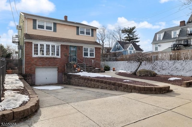 view of front of property featuring driveway, a garage, a chimney, and brick siding