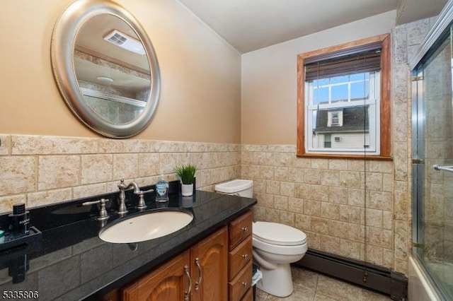 bathroom featuring toilet, a baseboard radiator, tile patterned floors, vanity, and tile walls