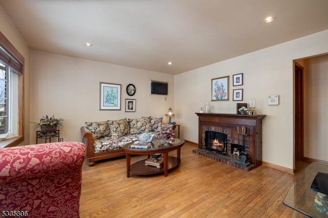 living room featuring light wood-type flooring, a fireplace, baseboards, and recessed lighting