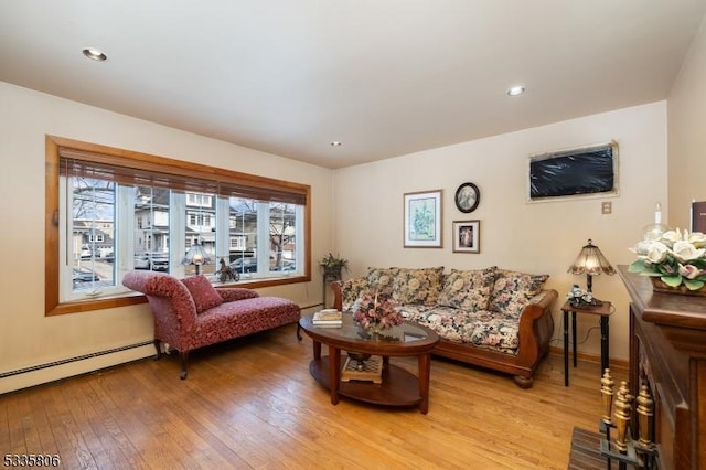 living room with a baseboard heating unit, recessed lighting, and light wood-style flooring