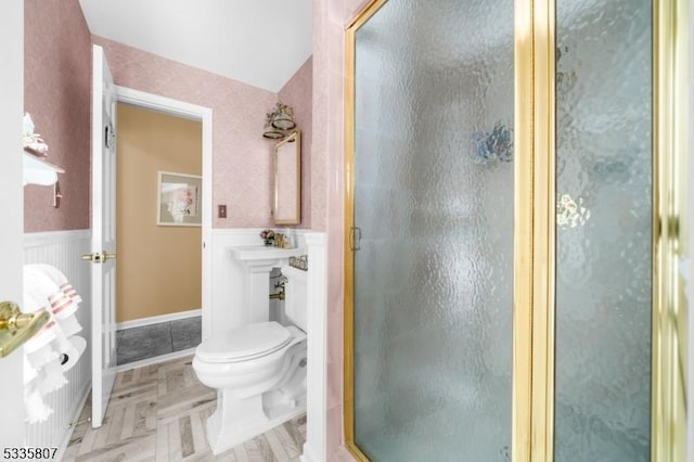 bathroom featuring parquet flooring, toilet, and a shower with shower door