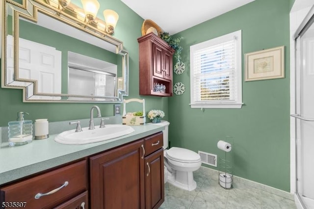 bathroom featuring a shower with door, vanity, and toilet