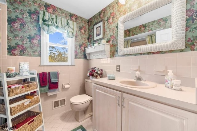 bathroom with vanity, toilet, tile patterned flooring, and tile walls