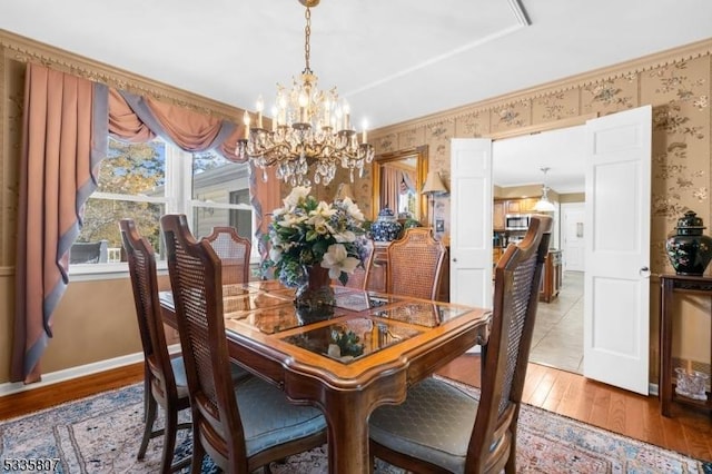 dining area featuring ornamental molding, an inviting chandelier, and light wood-type flooring