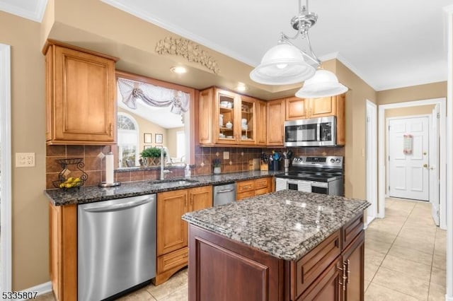 kitchen featuring sink, hanging light fixtures, dark stone counters, ornamental molding, and stainless steel appliances