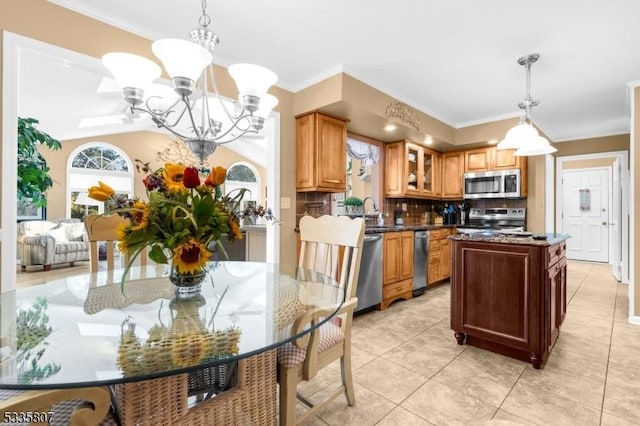 kitchen featuring an inviting chandelier, hanging light fixtures, backsplash, stainless steel appliances, and a kitchen island