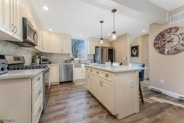 kitchen with sink, a center island, hanging light fixtures, stainless steel appliances, and decorative backsplash