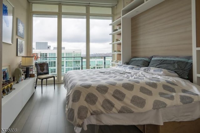 bedroom with a wall of windows, hardwood / wood-style floors, and access to outside