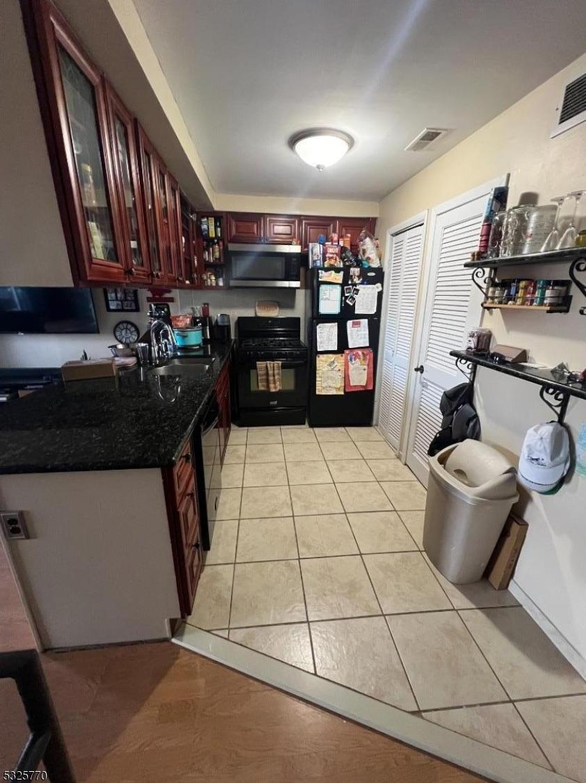 kitchen featuring sink, light tile patterned floors, and black appliances