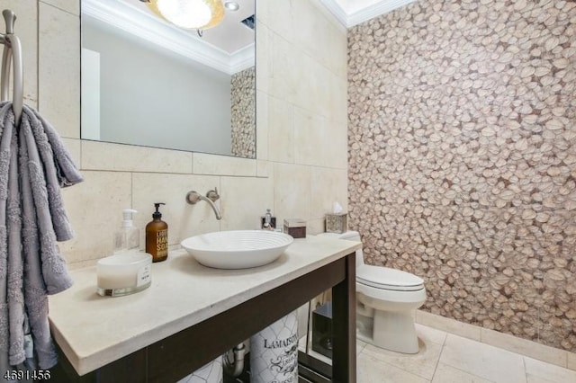 bathroom with tile patterned floors, toilet, sink, tile walls, and ornamental molding