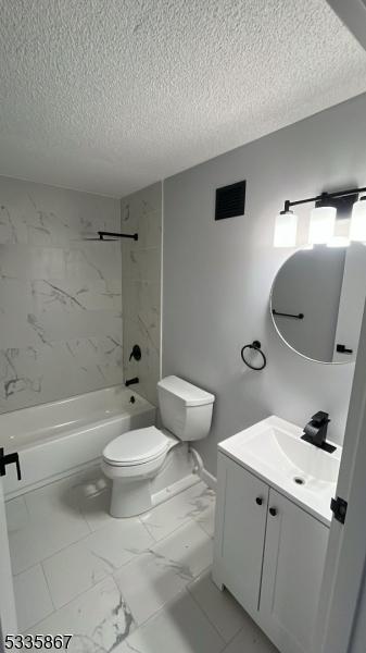 full bathroom featuring vanity, toilet, a textured ceiling, and tiled shower / bath