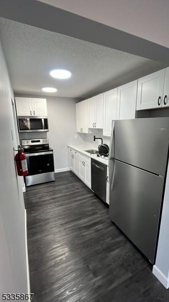 kitchen featuring sink, dark wood-type flooring, stainless steel appliances, a textured ceiling, and white cabinets