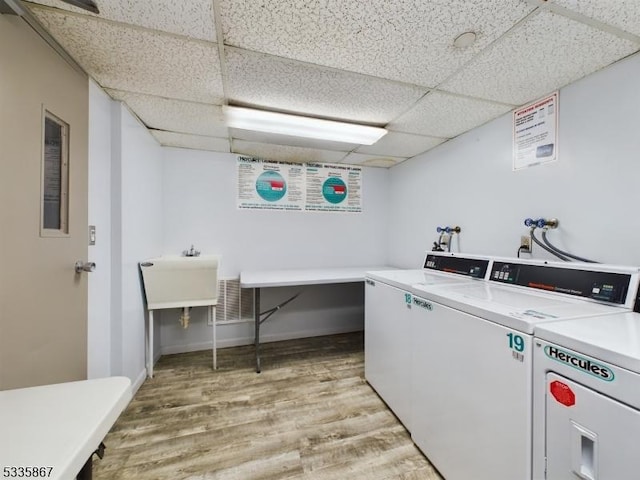 clothes washing area featuring washing machine and clothes dryer and light wood-type flooring