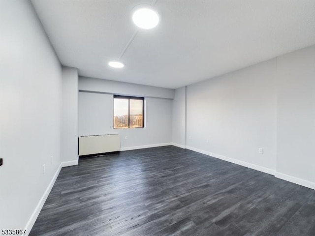 unfurnished room featuring dark hardwood / wood-style flooring and radiator