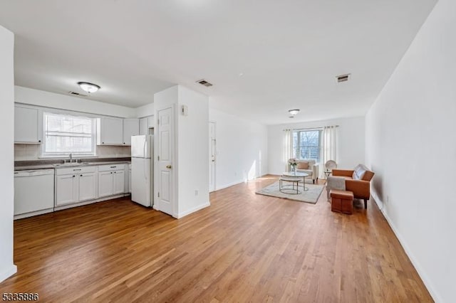 kitchen featuring white cabinetry, white appliances, a healthy amount of sunlight, and light wood-type flooring