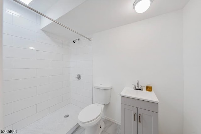 bathroom featuring tiled shower, vanity, and toilet