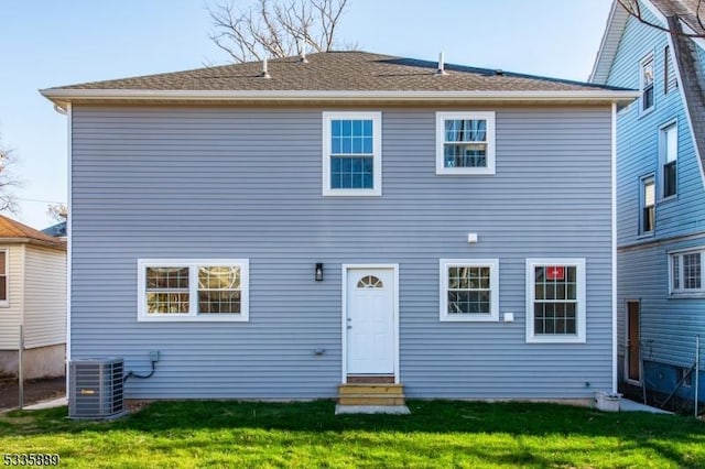 rear view of property with central AC unit and a yard