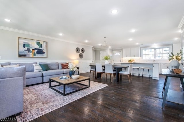 living room with a notable chandelier, ornamental molding, and dark hardwood / wood-style floors