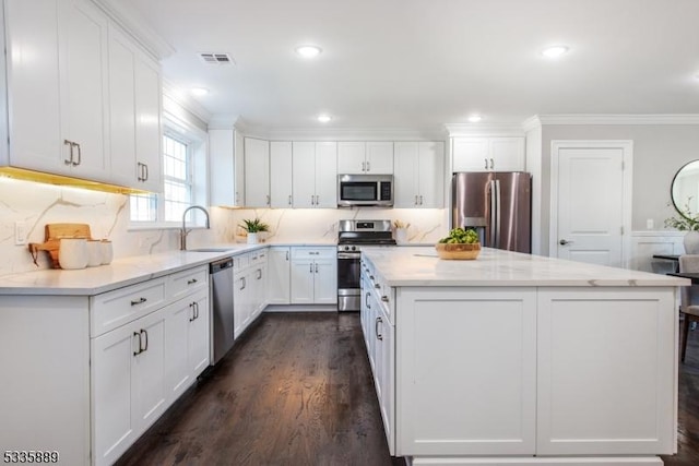 kitchen with sink, stainless steel appliances, dark hardwood / wood-style floors, white cabinets, and a kitchen island