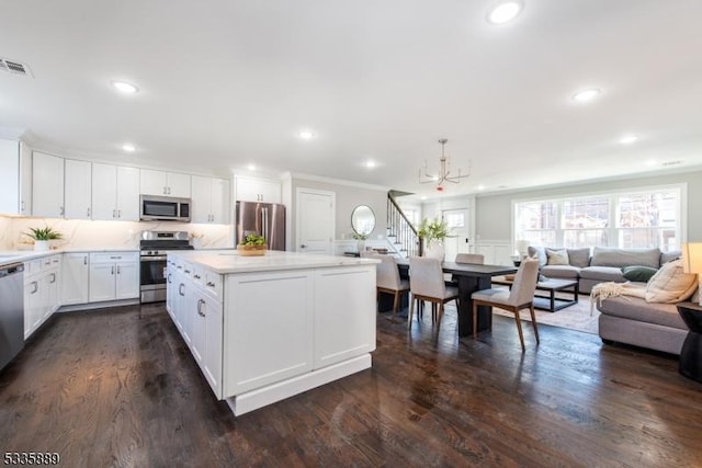 kitchen featuring appliances with stainless steel finishes, dark hardwood / wood-style floors, a center island, white cabinets, and a chandelier