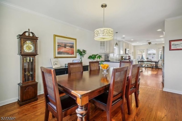 dining space with crown molding, ceiling fan, sink, and hardwood / wood-style floors