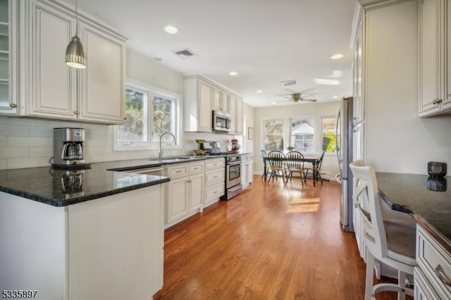 kitchen featuring hardwood / wood-style floors, decorative light fixtures, tasteful backsplash, sink, and stainless steel appliances