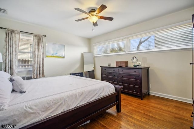 bedroom featuring ceiling fan, dark hardwood / wood-style flooring, and multiple windows