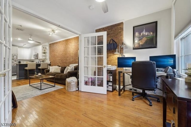 office area featuring french doors, ceiling fan, brick wall, and light hardwood / wood-style floors