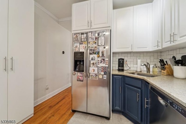 kitchen with appliances with stainless steel finishes, blue cabinets, sink, and white cabinets