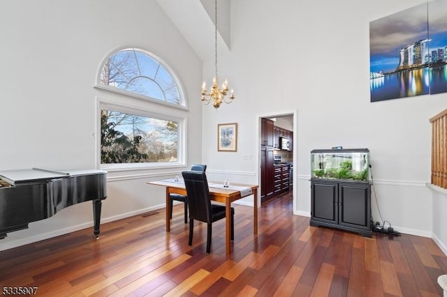 dining area with a chandelier, high vaulted ceiling, dark wood finished floors, and baseboards