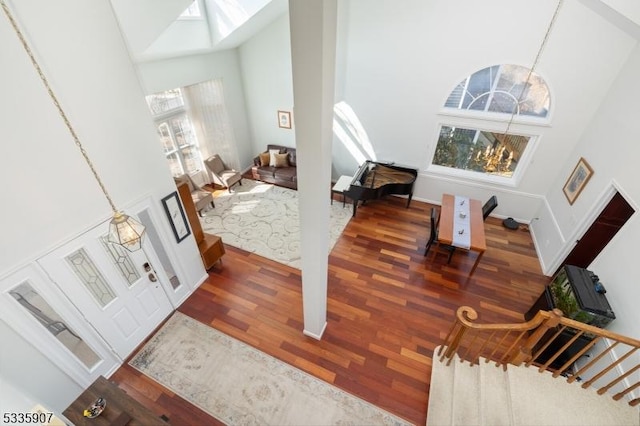 entryway with a chandelier, stairs, wood finished floors, and a towering ceiling