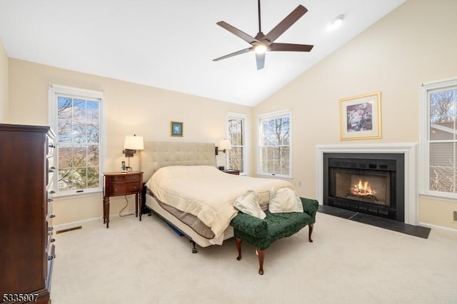 carpeted bedroom with visible vents, a fireplace with flush hearth, ceiling fan, high vaulted ceiling, and baseboards