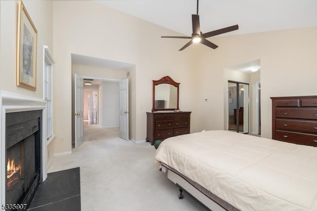 bedroom with high vaulted ceiling, a fireplace with flush hearth, baseboards, and light colored carpet