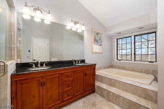 bathroom featuring vaulted ceiling, a garden tub, a sink, and double vanity