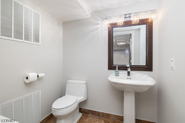 half bathroom featuring toilet, baseboards, visible vents, and a sink