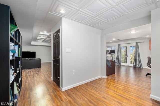 hallway featuring french doors, wood finished floors, and baseboards